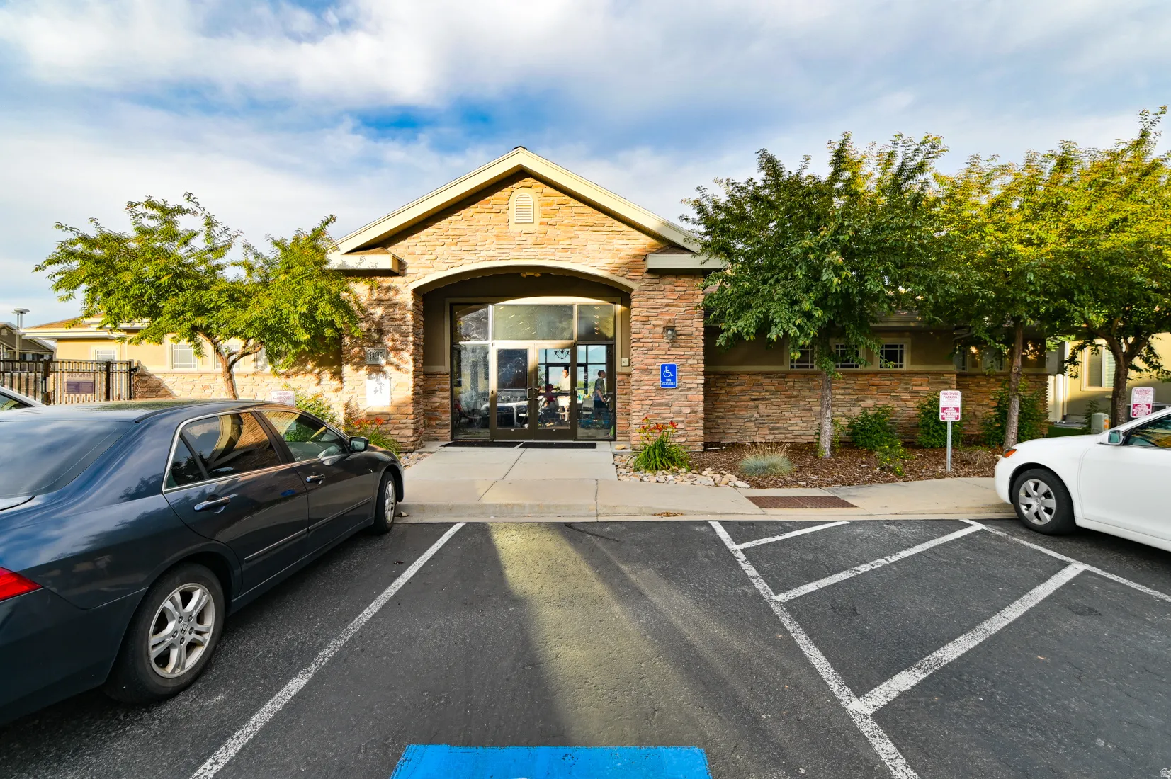 Stone facade entry with arched portico, large glass entry doors, and dedicated parking