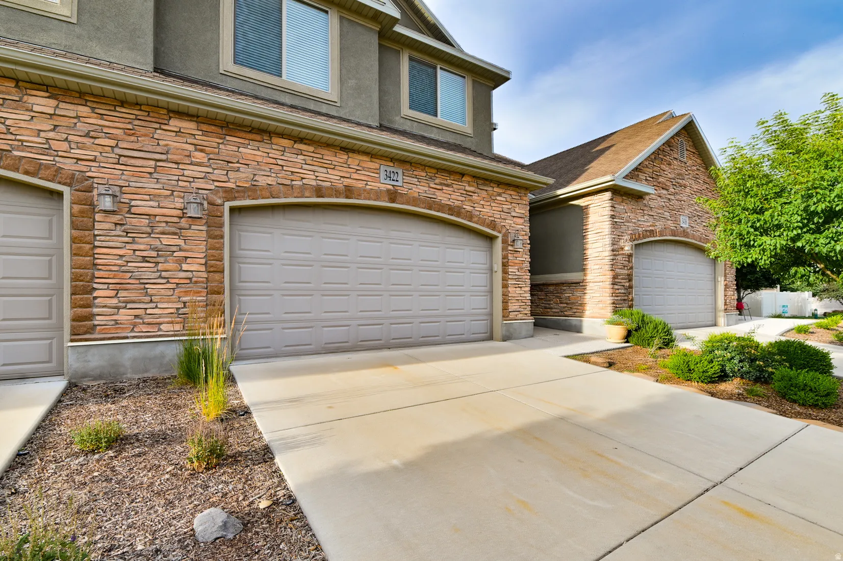 Stone veneer facade featuring arched garage door openings