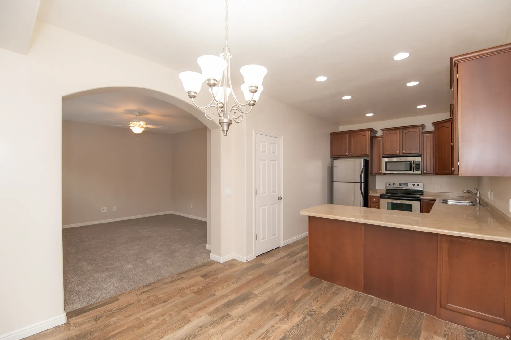 Kitchen and dining area featuring wood-finish flooring, recessed lighting, a chandelier, wood cabinetry, and stainless steel appliances