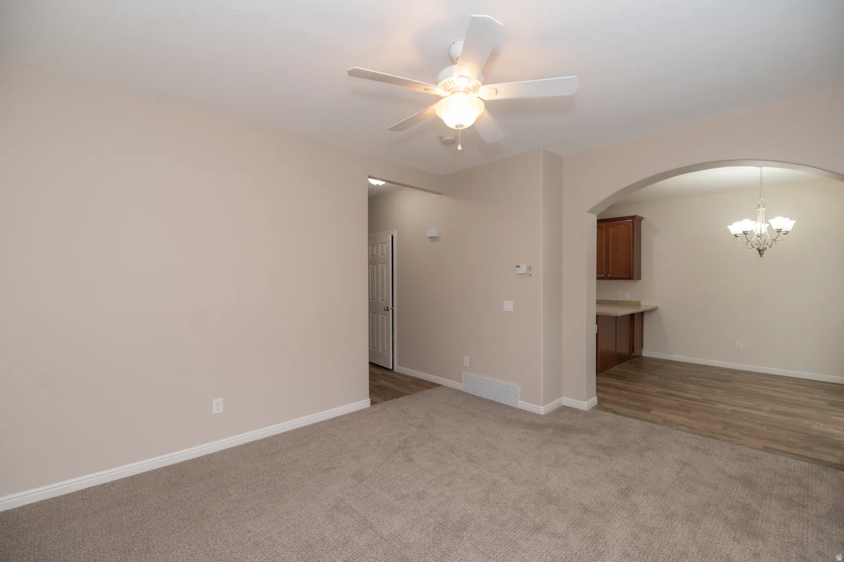Living space featuring neutral carpeting and a ceiling fan with integrated lighting