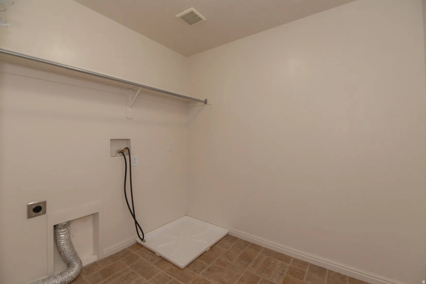 Dedicated laundry space featuring a utility sink connection, dryer vent, washer hookups, and a built-in hanging rod with shelving