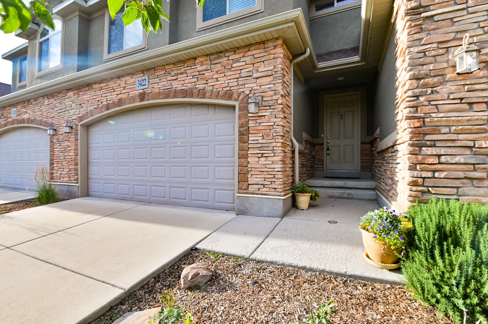 Stone veneer facade featuring two individual garage doors with arched stone accents