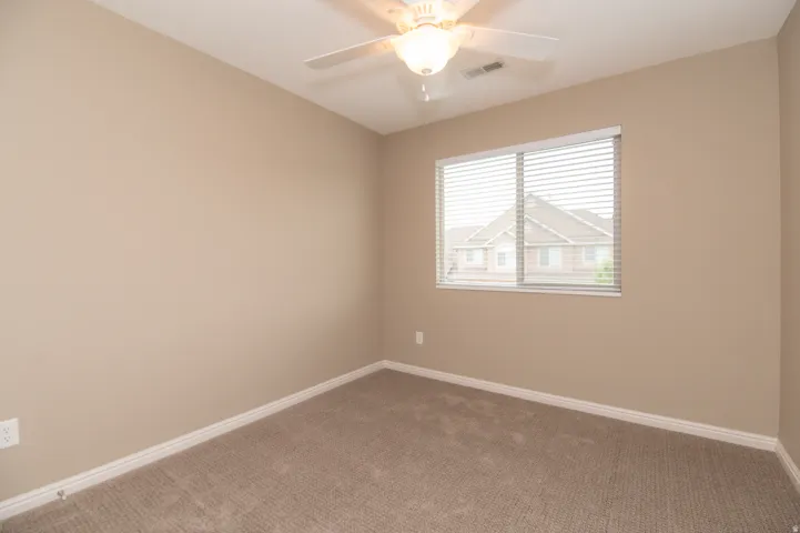 Spacious room featuring neutral carpeting, light beige wall paint, and white baseboards