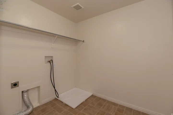 Dedicated laundry space featuring a utility sink connection, dryer vent, washer hookups, and a built-in hanging rod with shelving