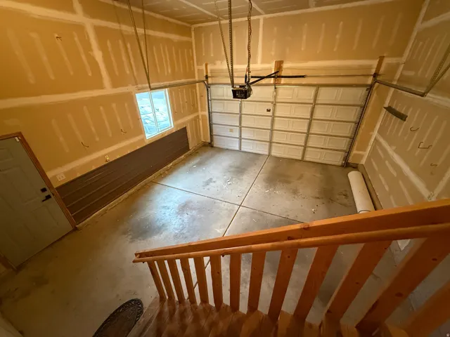Two-car garage with a paneled overhead door, concrete flooring, and an entry door