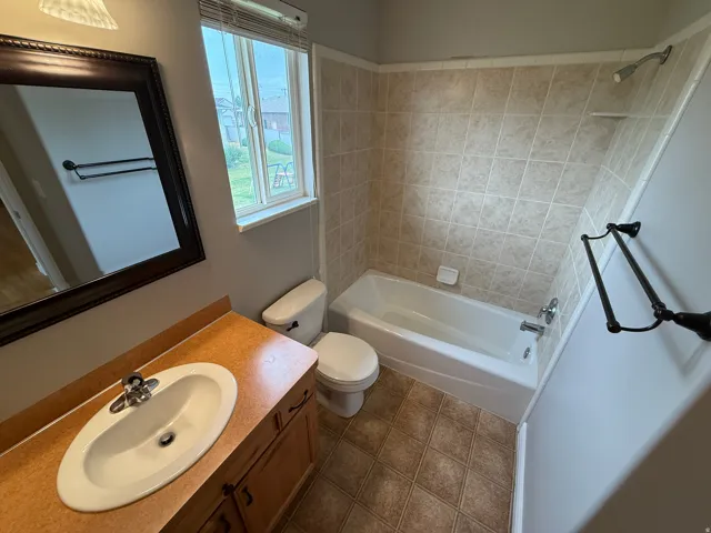 Bathroom featuring a single vanity with an integrated sink, a built-in bathtub, and ceramic tile flooring