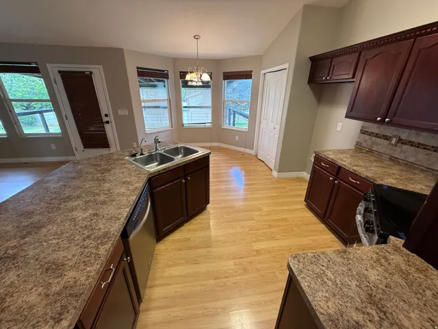 Kitchen featuring warm-toned wood-finish flooring, dark wood cabinetry, and speckled countertops
