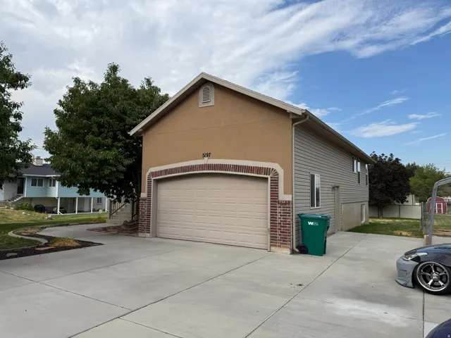 Exterior featuring a tan stucco finish, brick accents, a two-car garage, and a concrete driveway
