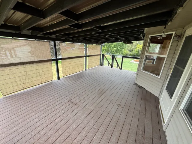 Spacious covered deck featuring composite wood-finish flooring, a wood-paneled ceiling, and exterior privacy screens