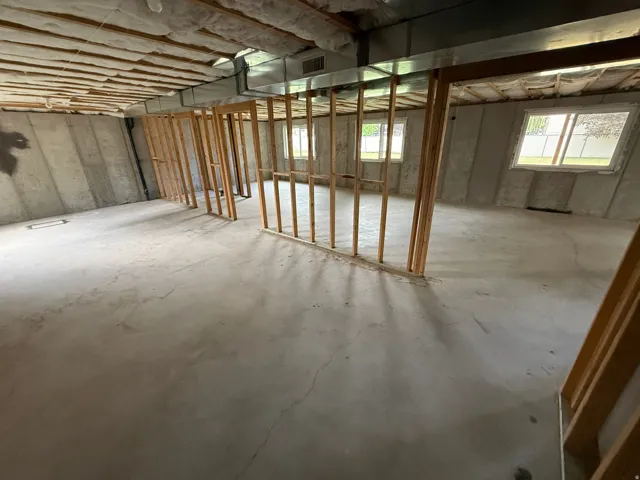 Unfinished basement featuring concrete flooring, exposed ceiling insulation, and visible ductwork