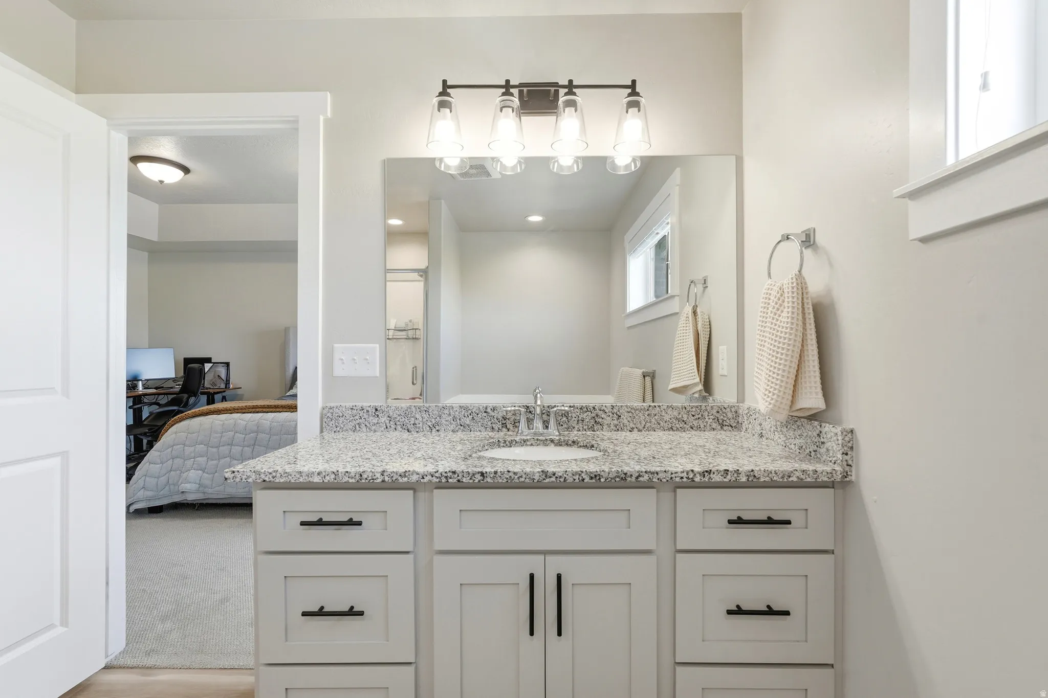 Vanity with a speckled countertop, undermount sink, and dark-finish hardware