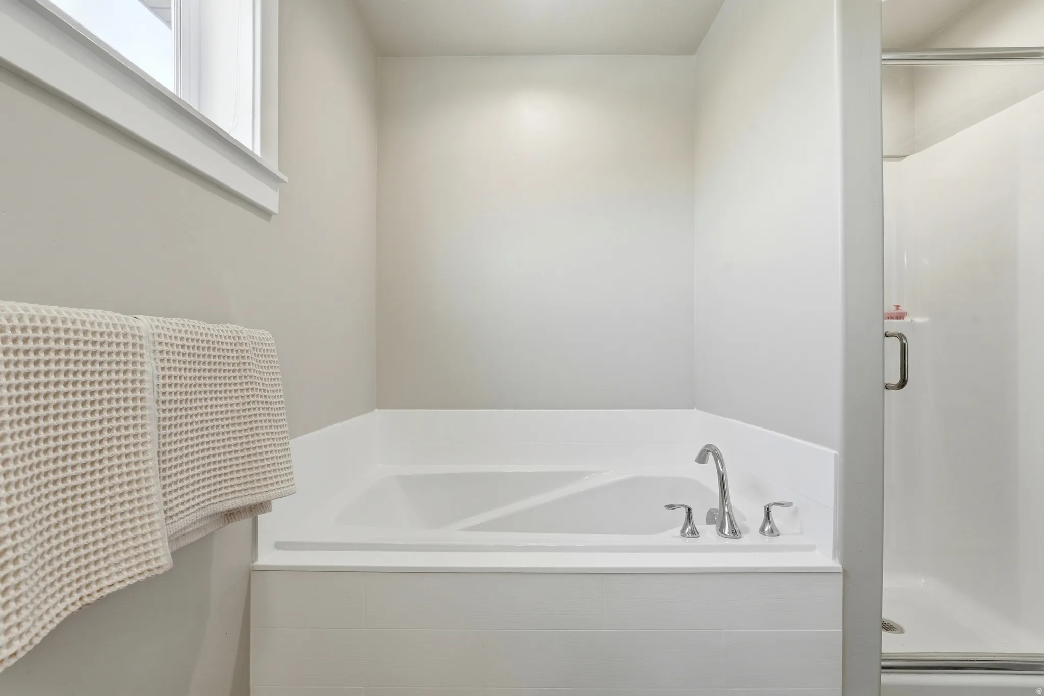 Built-in corner bathtub with polished chrome fixtures and a surrounding white tile enclosure