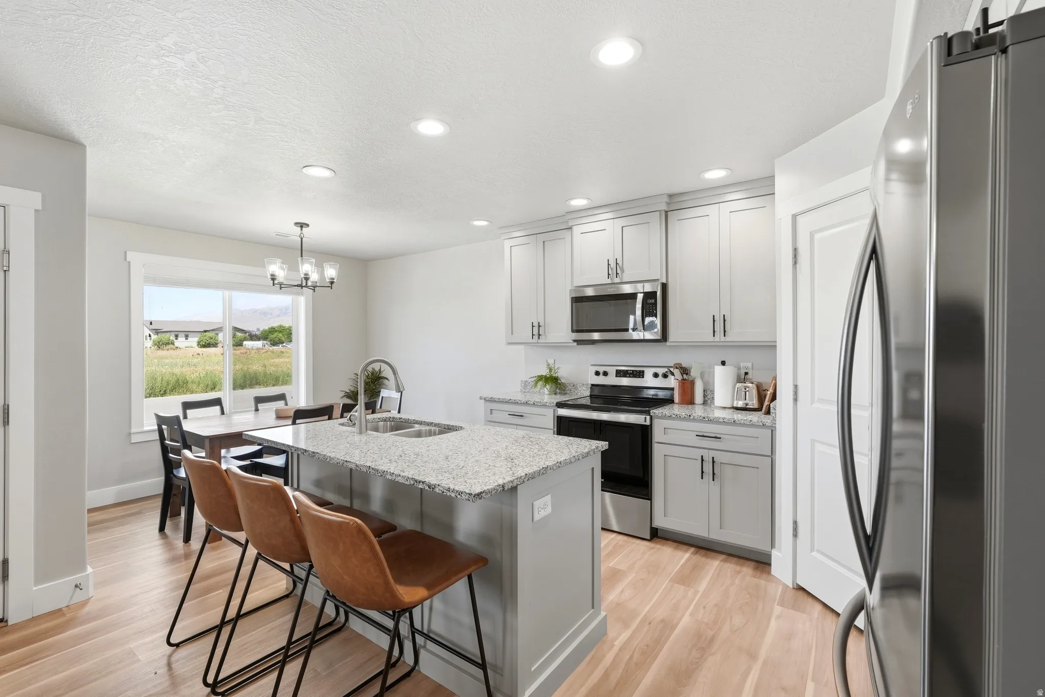 Modern kitchen featuring light gray cabinetry, granite countertops, and stainless steel appliances