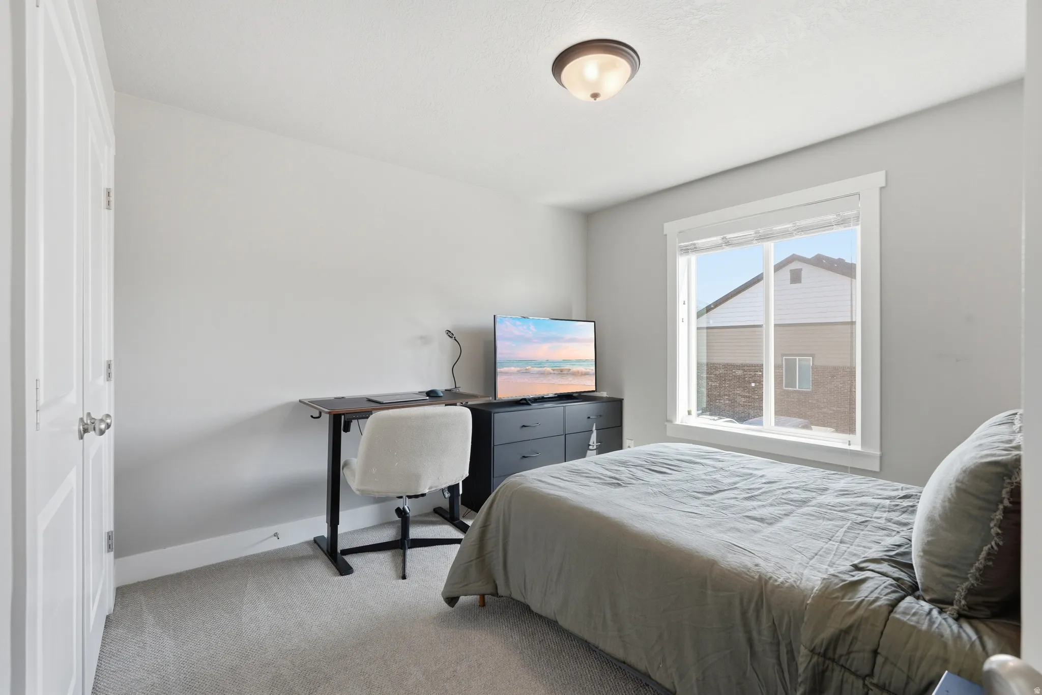 Carpeted room featuring a white-framed window, neutral painted walls, and a semi-flush mount ceiling light