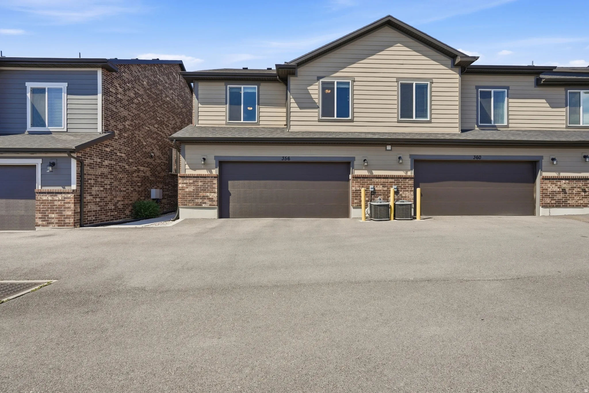 Multi-unit building featuring horizontal siding, brick veneer accents, and dark brown garage doors