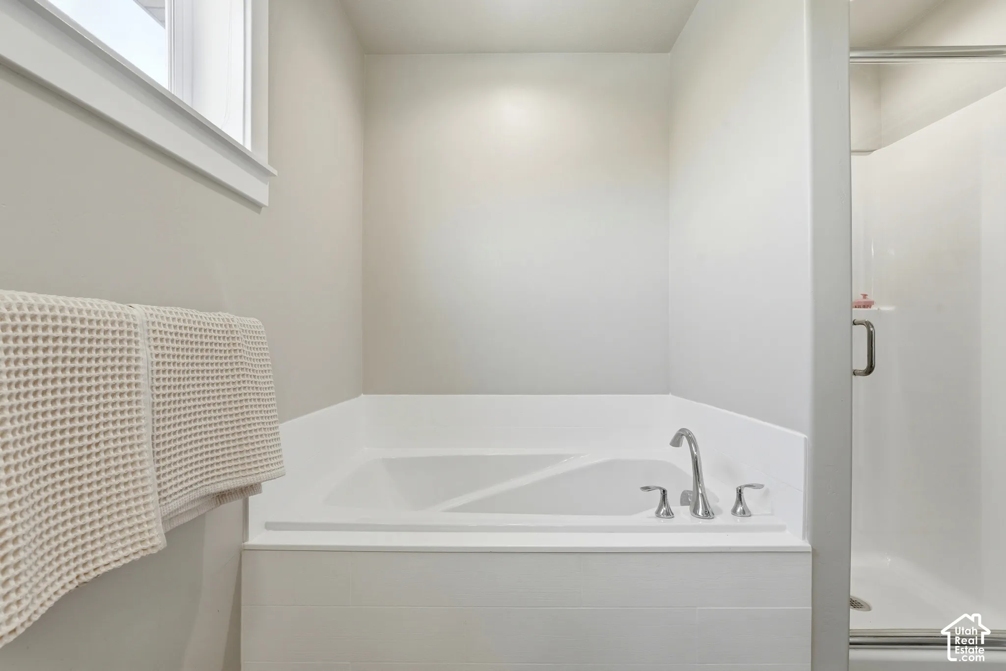 Built-in corner bathtub with polished chrome fixtures and a surrounding white tile enclosure