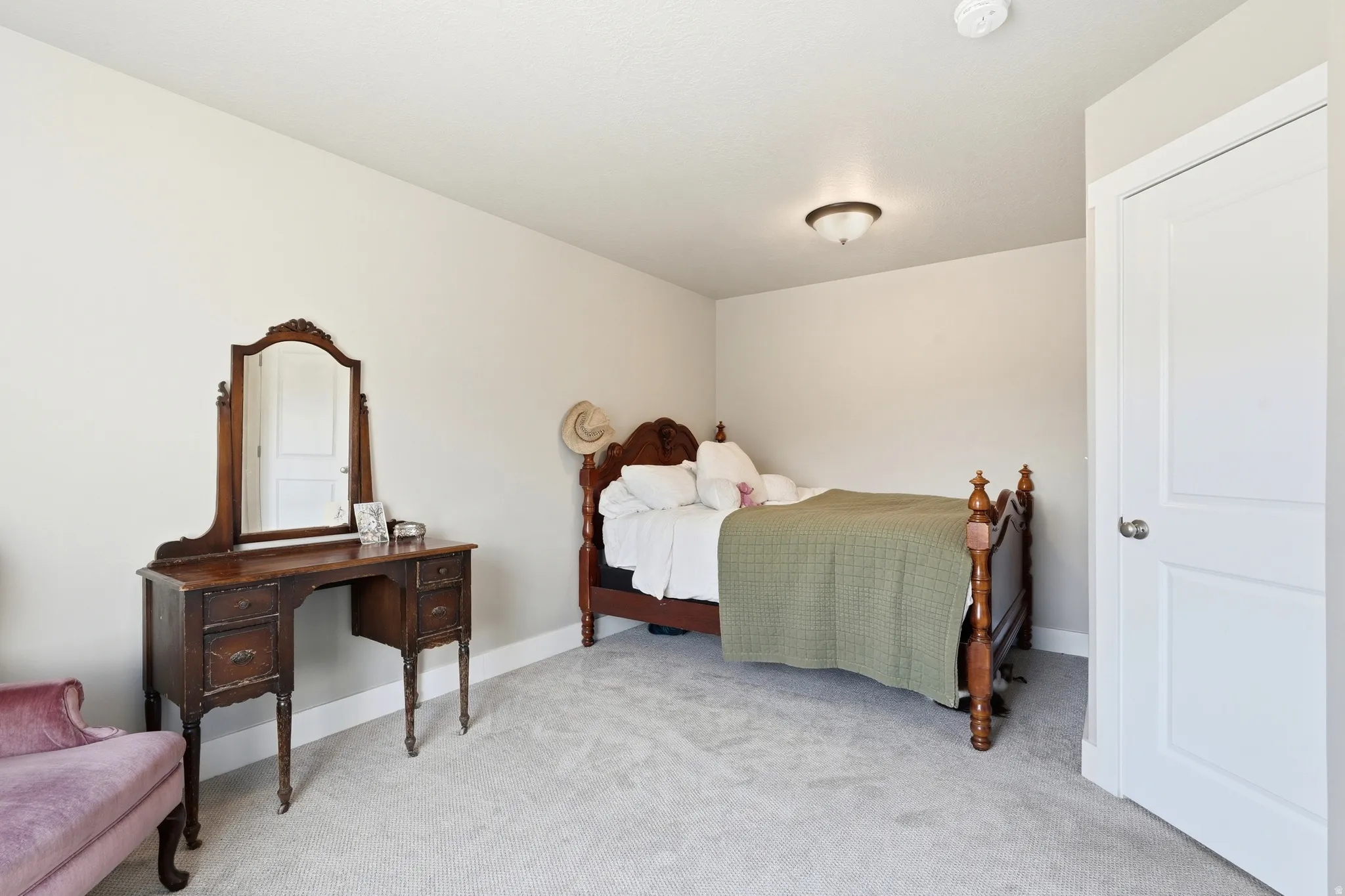 Neutral tone wall color, ceiling-mounted light fixture, white door with brushed nickel hardware, and light-colored carpeting