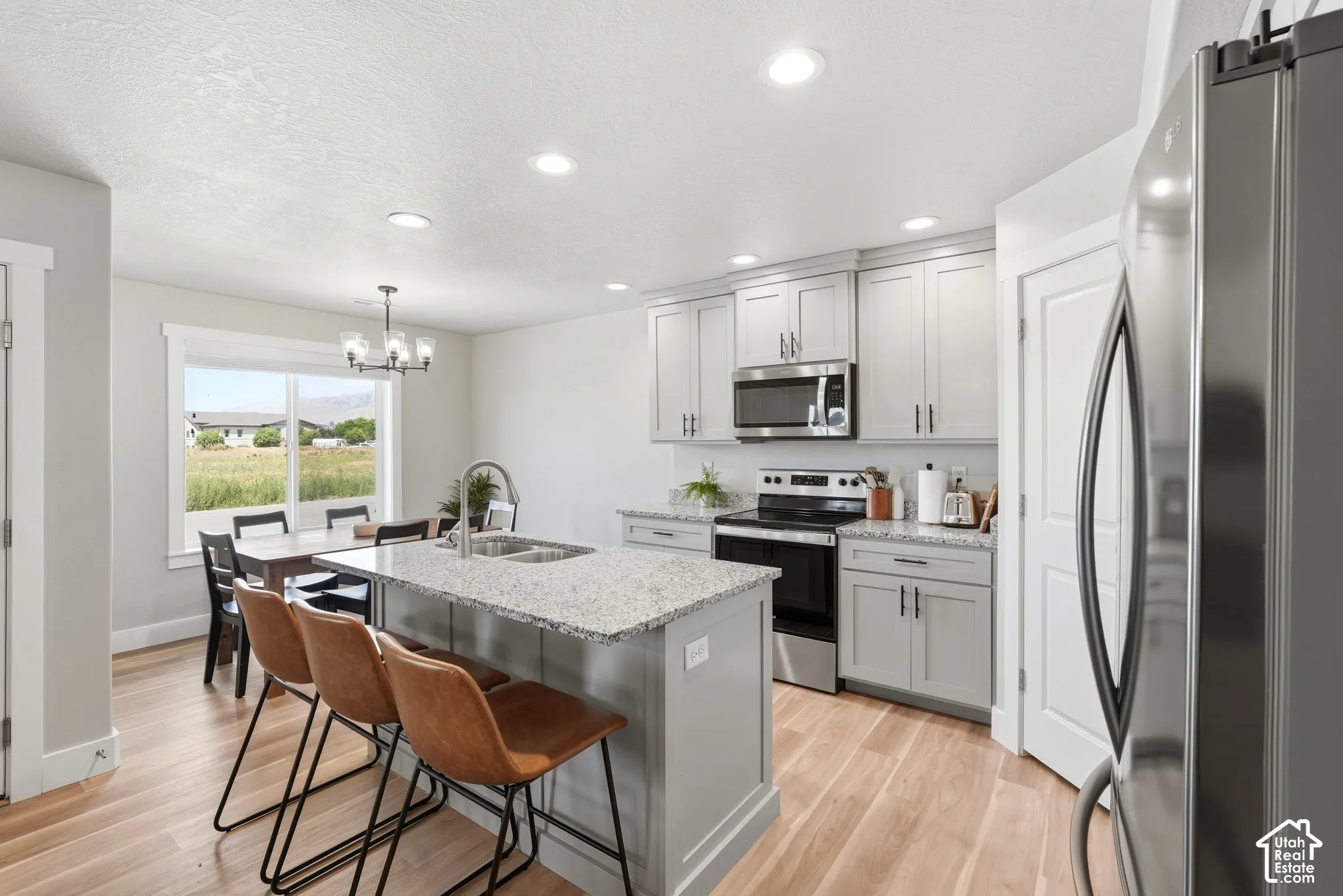 Modern kitchen featuring light gray cabinetry, granite countertops, and stainless steel appliances