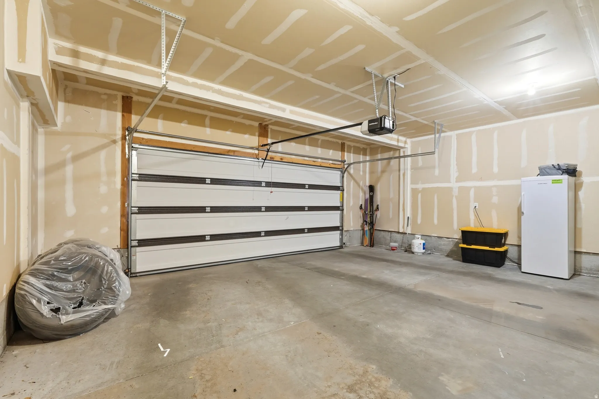 Spacious garage featuring an automatic overhead door, unfinished drywall, and concrete flooring