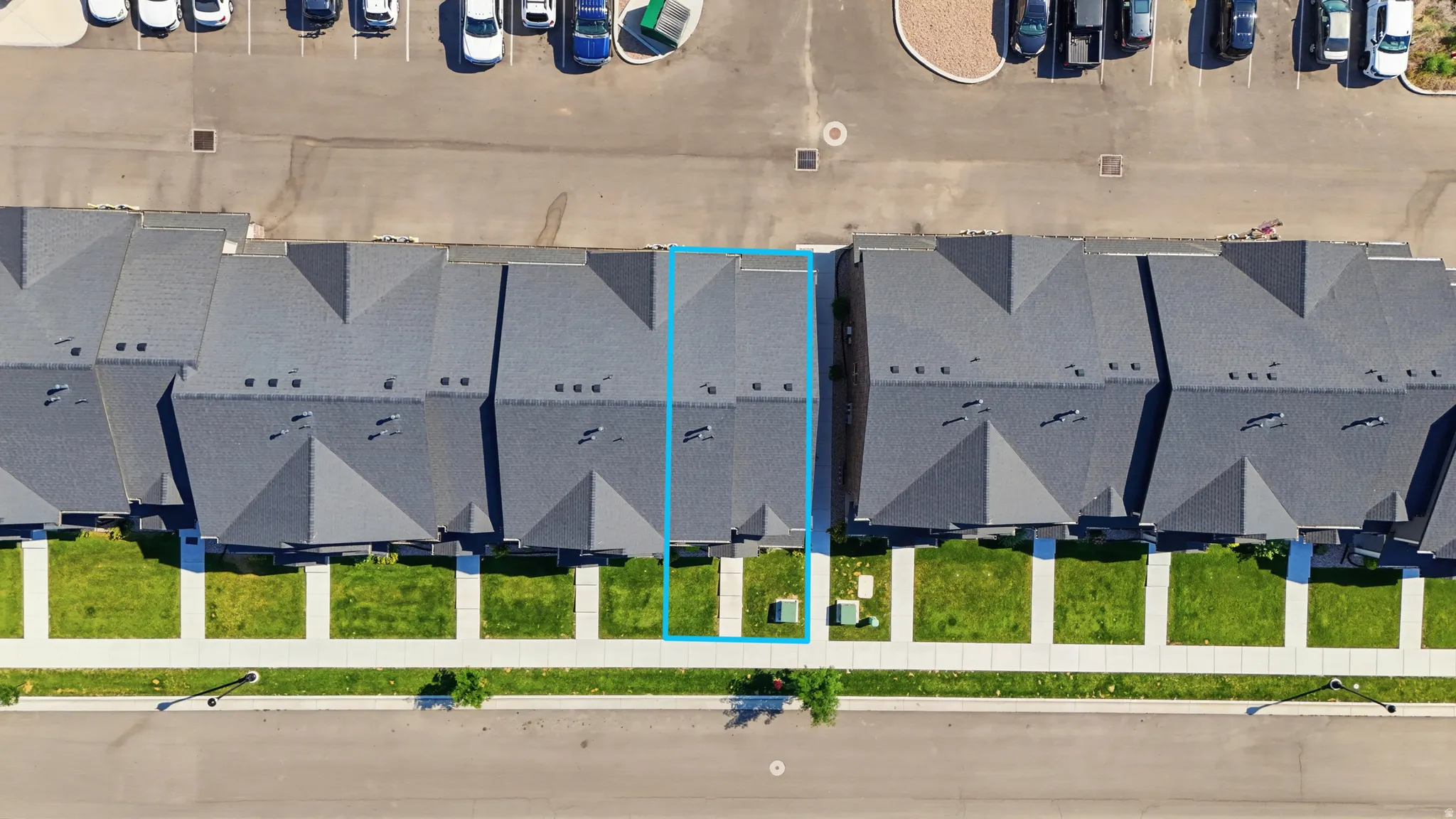 Townhome unit featuring a dark gray shingle roof, light gray exterior siding, and a concrete sidewalk leading to the entrance