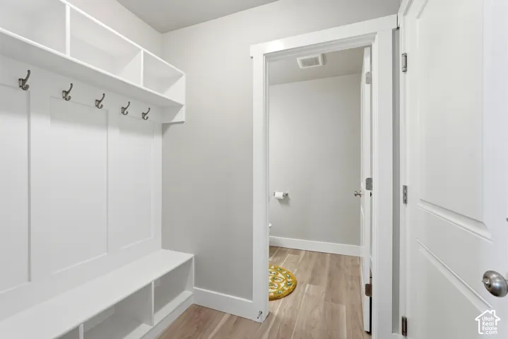Built-in white storage unit featuring a bench, open shelving, and coat hooks