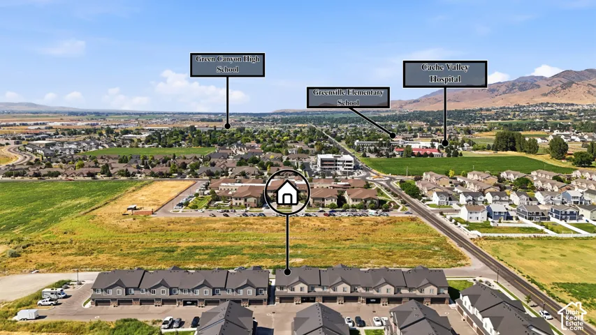 Aerial perspective highlighting the property within a residential setting, featuring mountains in the background and a road in the foreground