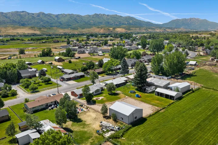 Expansive rural landscape featuring a mix of residential properties, agricultural fields, mature trees, and mountainous terrain in the background