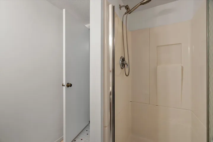Shower enclosure with a hand-held showerhead and built-in shelving
