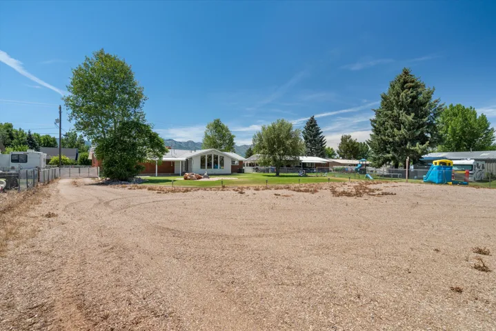 Spacious lot with a gravel foreground and a distant single-story residence