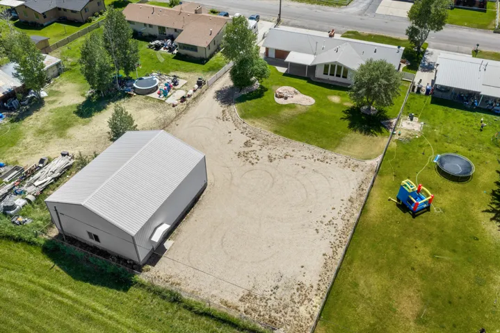 Expansive property featuring a large metal-sided outbuilding with a corrugated metal roof, a gravel-surfaced area, and a grassy lawn
