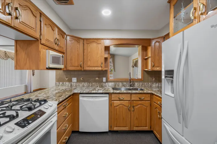 Kitchen featuring wood cabinetry, granite-finish countertops, and a tile backsplash