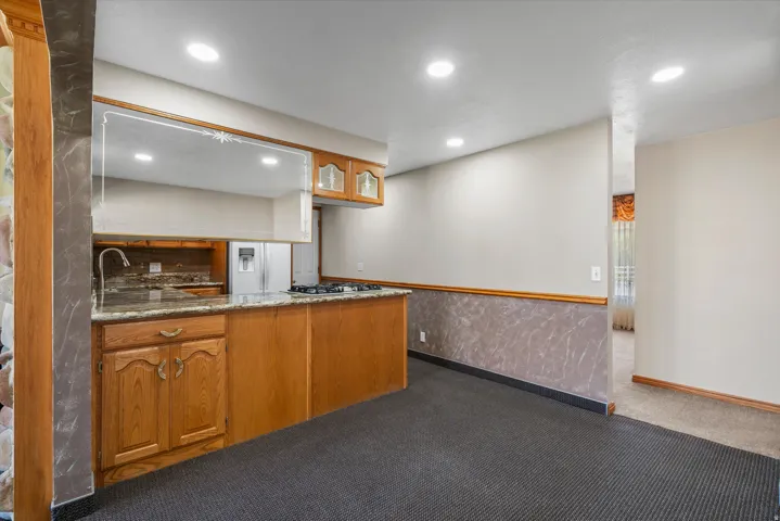 Kitchen featuring granite countertops, wood cabinetry, a gas cooktop, and an undermount sink with a gooseneck faucet