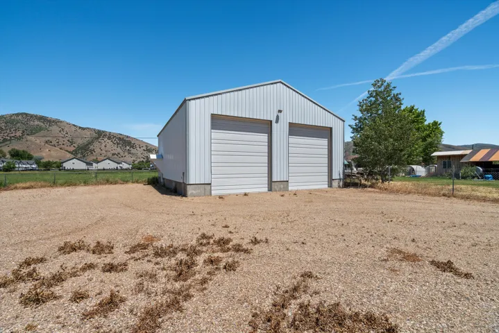 Metal outbuilding with two garage doors, set on a gravel lot