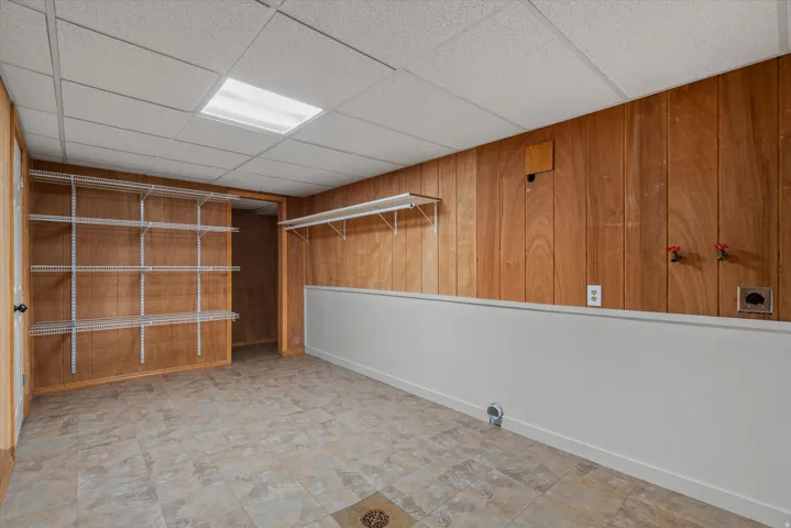 Utility space featuring wood-finish paneling, white wainscoting, and tile-pattern flooring