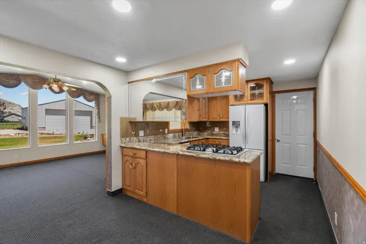 Kitchen with wood cabinetry, granite-style countertops, and a built-in gas cooktop