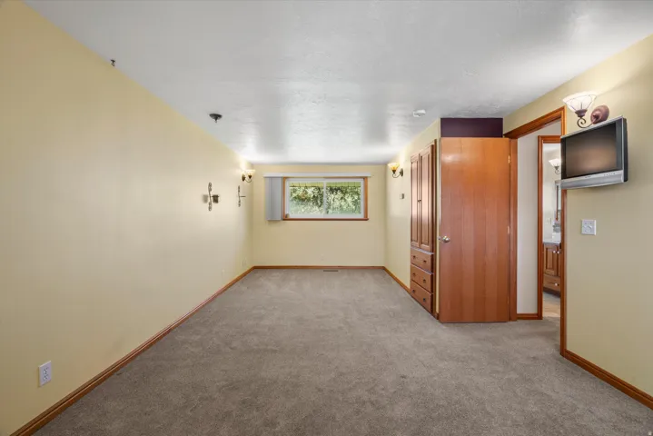 Carpeted room with a single window and wood-finish trim