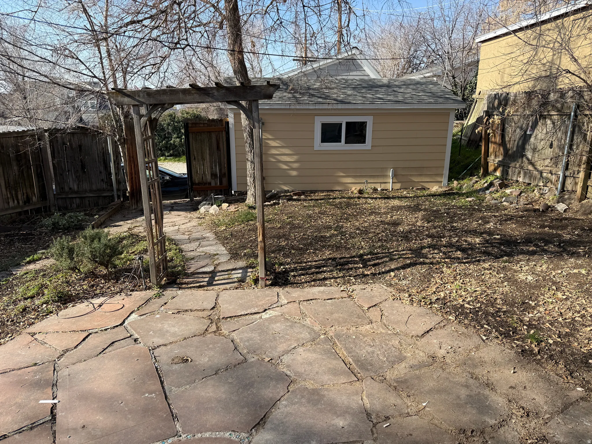 Flagstone patio area with an archway leading to a paved pathway