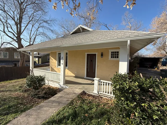 Welcoming front porch featuring white railing, light yellow stucco exterior, dark wood-finish entry door, and a multi-paned window