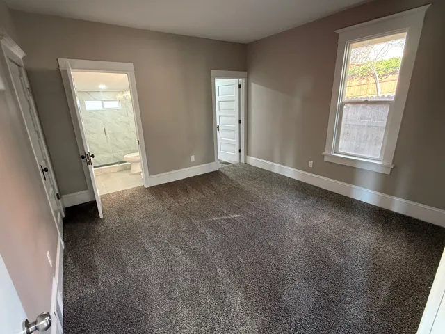 Carpeted room with neutral wall paint and white trim