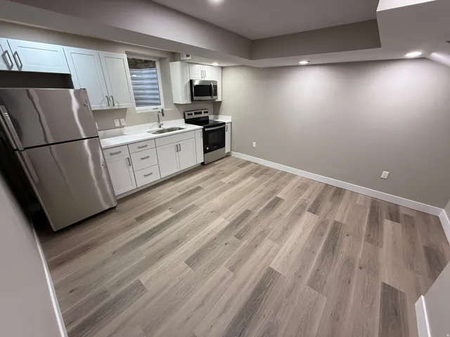 Contemporary kitchen space featuring wood-finish flooring, white cabinetry, stainless steel appliances, and recessed lighting