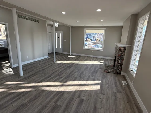 Spacious living area featuring wood-finish flooring, recessed lighting, and a stone-clad fireplace