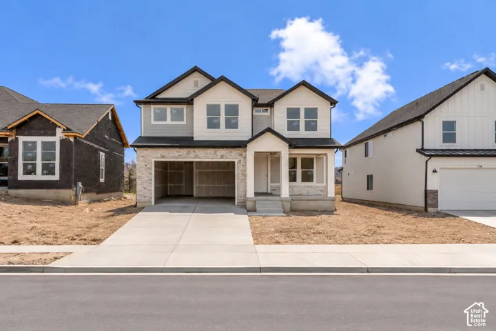 Two-story exterior featuring a mix of stone veneer and horizontal siding, dual-gabled roofline, covered front entry porch, and concrete driveway