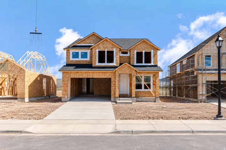Two-story construction featuring an attached garage, a paved driveway, and a shingled roof