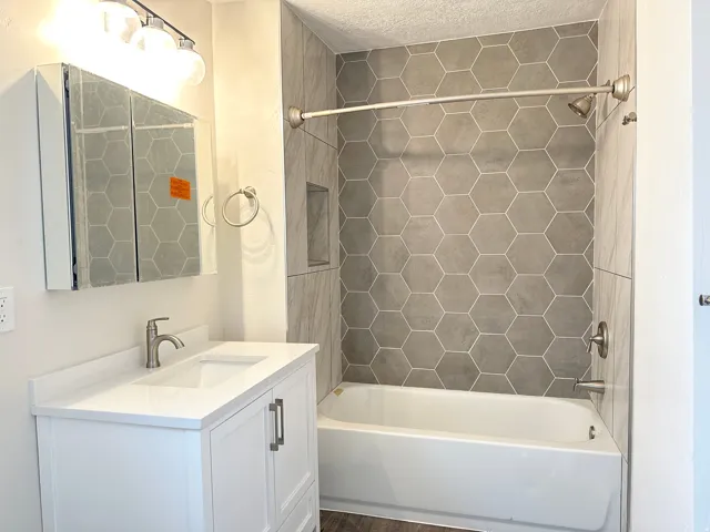 Bathroom featuring a white vanity with an integrated sink, brushed nickel faucet, and a mirrored medicine cabinet