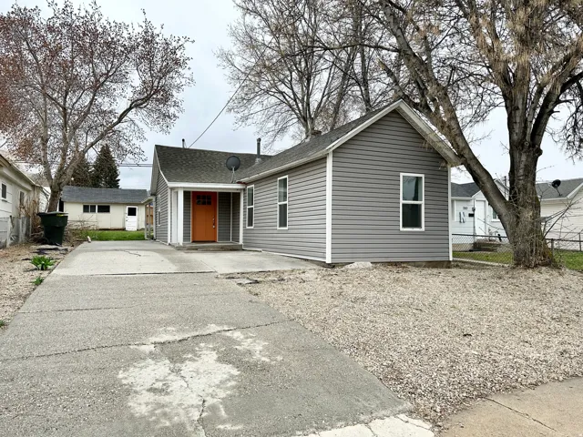 Gray siding exterior with white trim, featuring an orange front door and a covered entryway