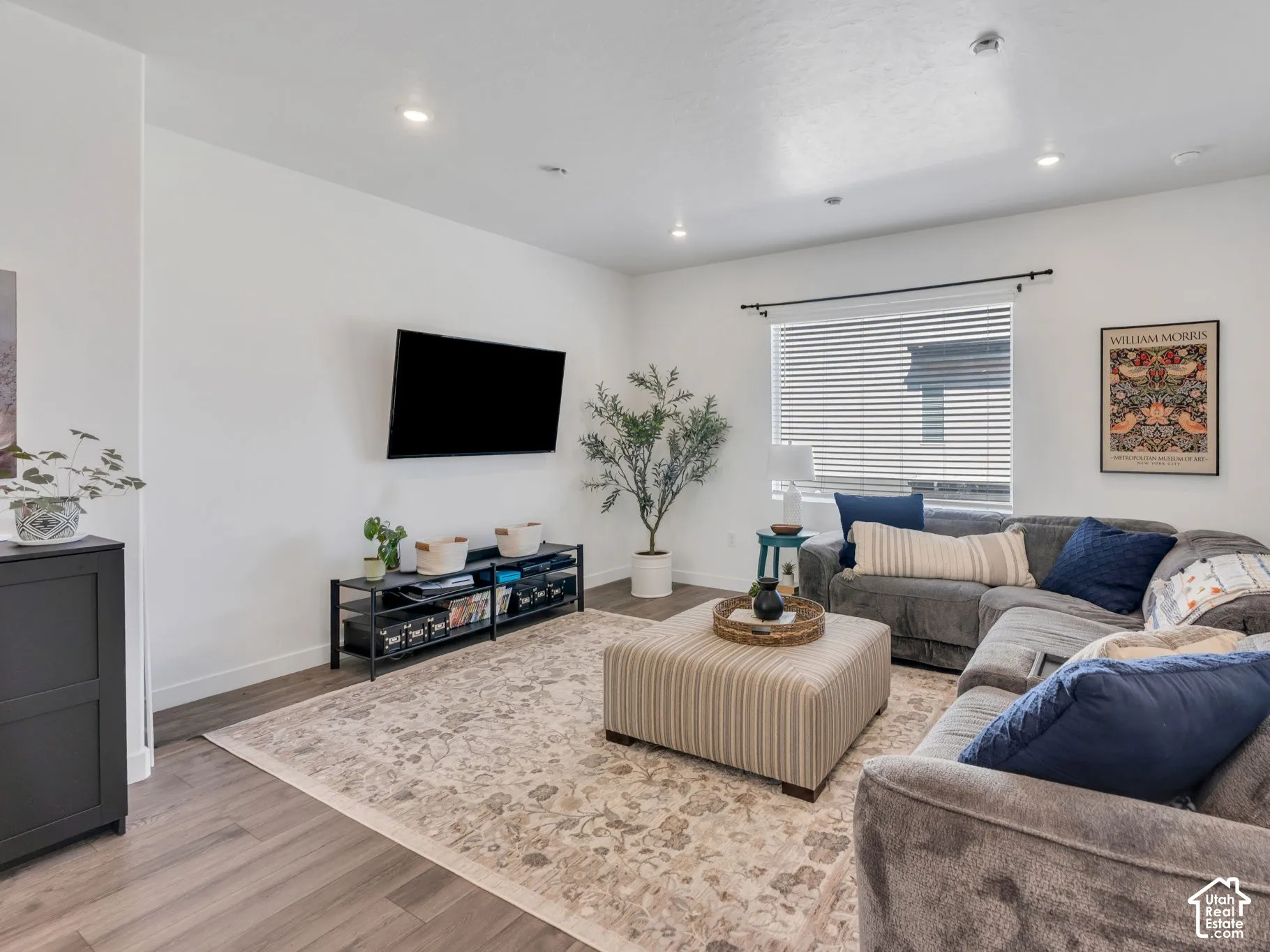 Recessed lighting, wood-finish flooring, and a large window with blinds