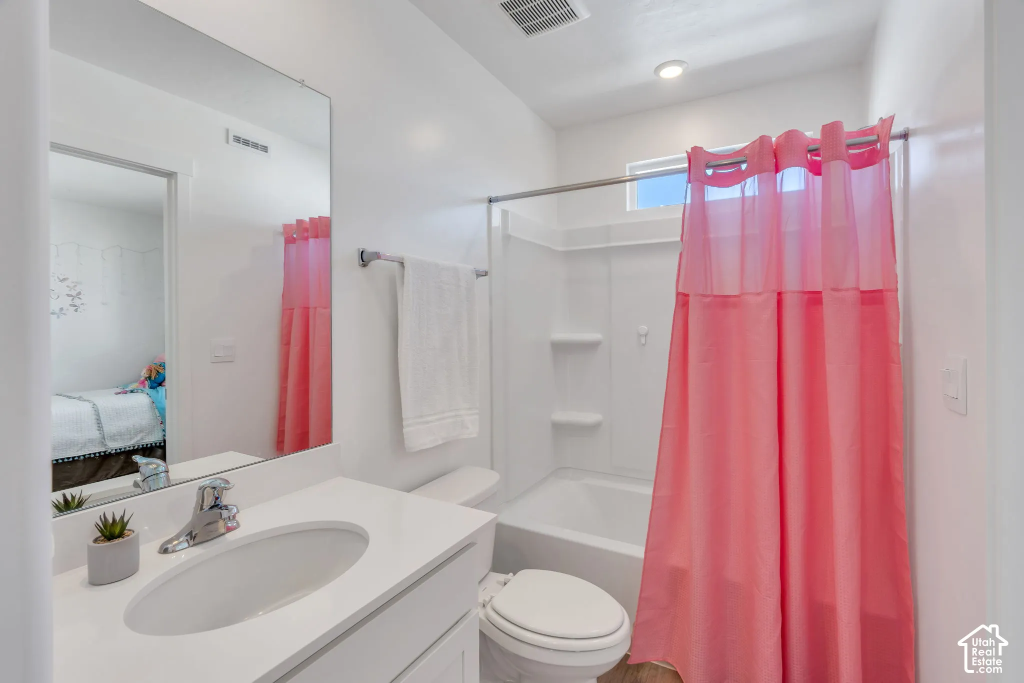 White vanity with integrated sink, chrome faucet, and expansive wall mirror