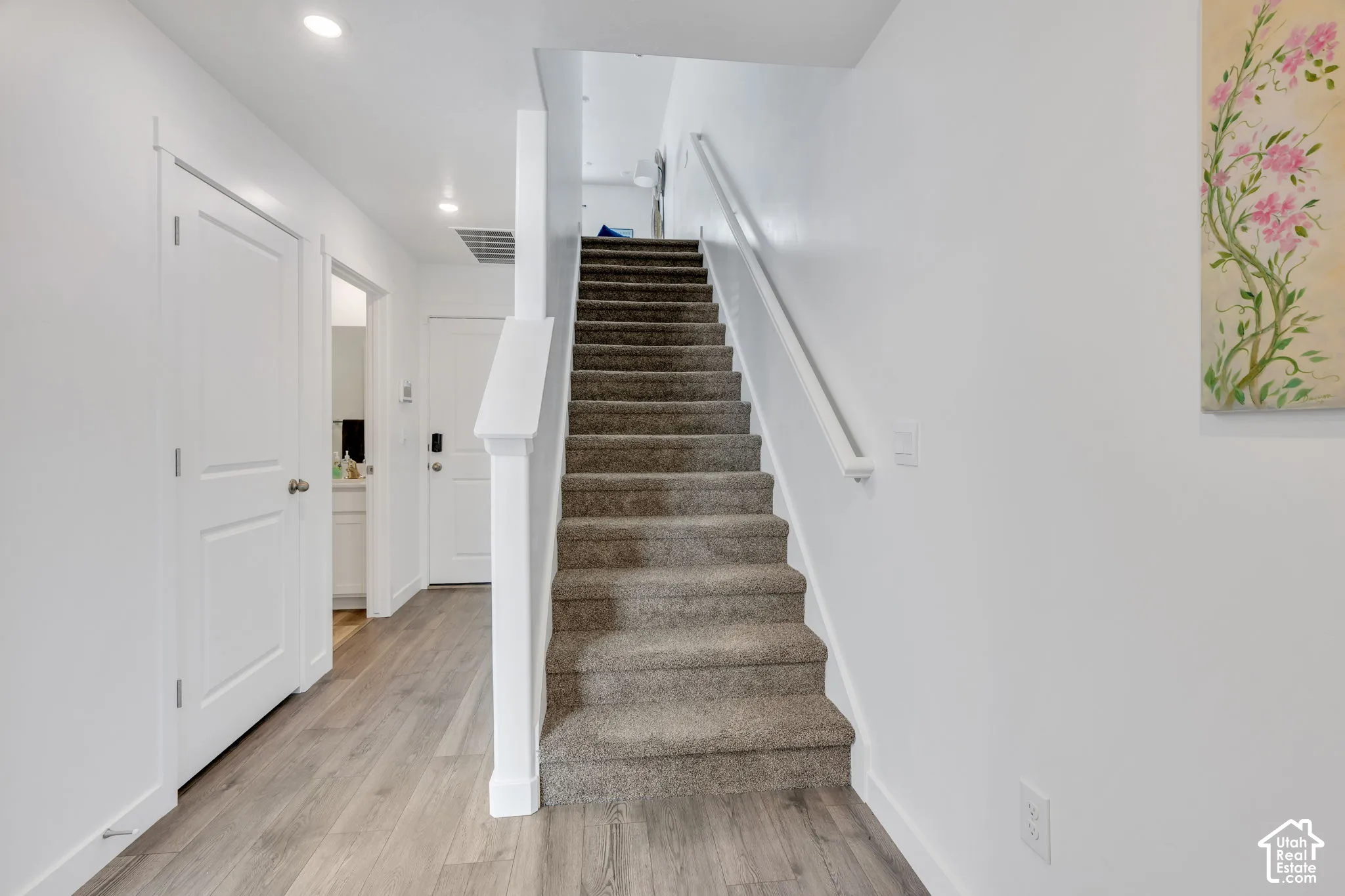 Wood-finish flooring, recessed ceiling lighting, carpeted staircase, and white interior doors