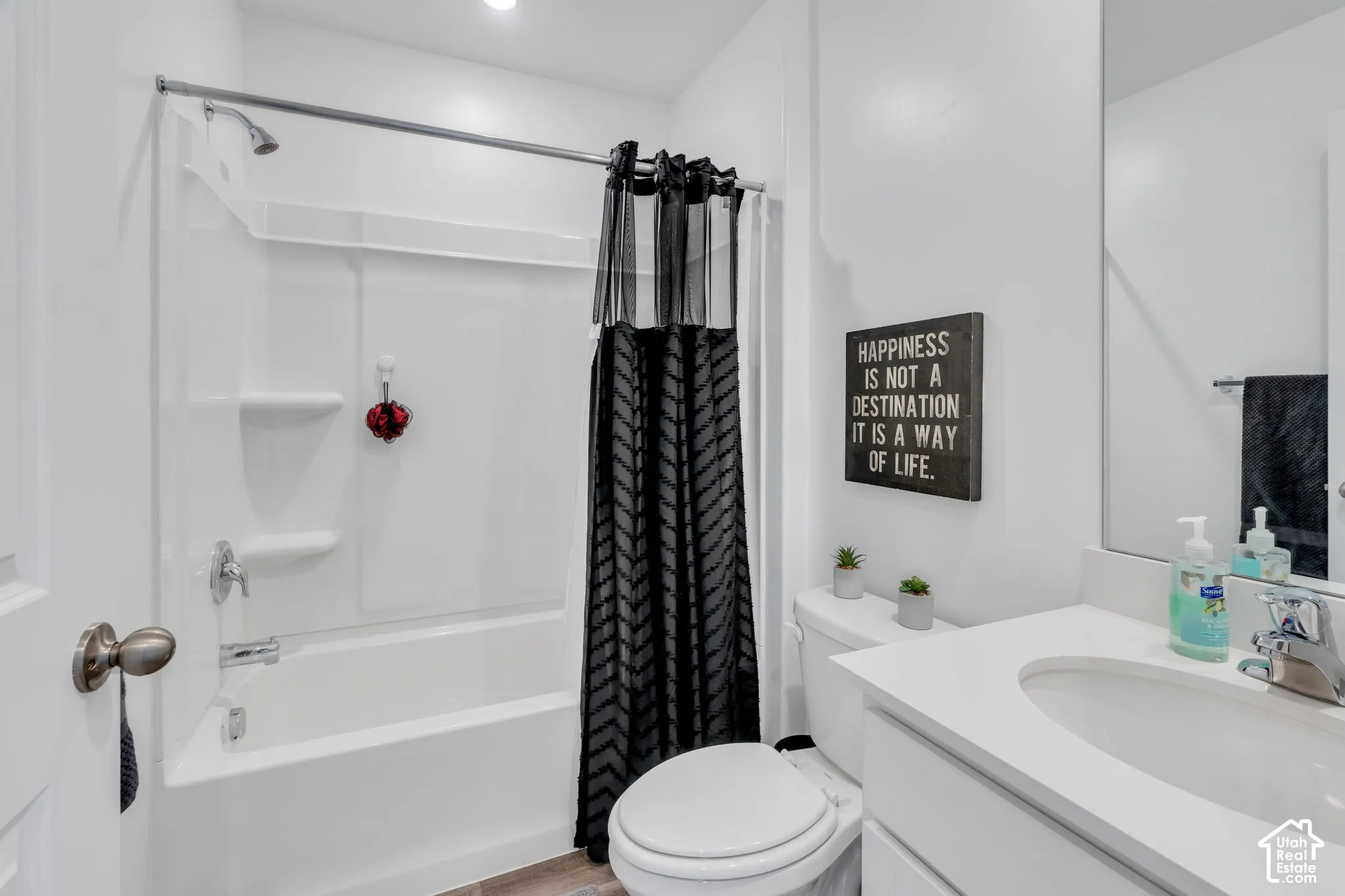 Integrated tub and shower combination, single vanity with an integrated sink, polished chrome fixtures, and wood-finish flooring