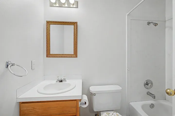 Bathroom featuring a wood-finish vanity with an integrated sink, a framed mirror, and a chrome light fixture